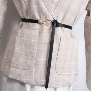 Detail of slim black faux leather belt with gold metal hook buckle on blazer coat