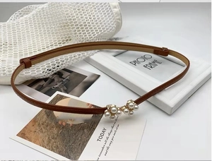 Détail d'une fine ceinture en cuir marron pour femmes avec boucle en perles élégante