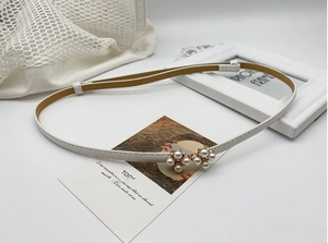 Détail de la ceinture en cuir blanc avec boucles élégantes ornées de grappes de perles
