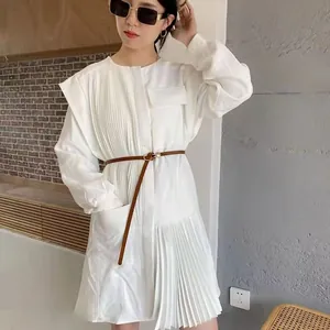 Detail of a thin brown waist belt on a white pleated long sleeve dress