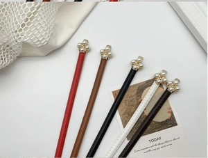 Détail de fines ceintures en cuir avec d'élégantes boucles en métal et fleurs de perles en 5 tons