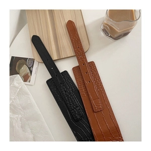 Détail de ceintures larges en cuir à motif crocodile en noir et marron chic