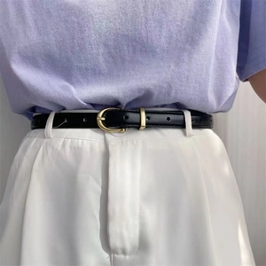 Ceinture fine noire minimaliste avec boucle fer à cheval dorée sur pantalon taille haute