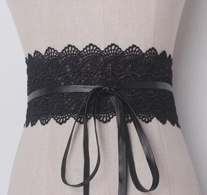 Detail of black wide lace corset belt with intricate floral patterns and tie-up front
