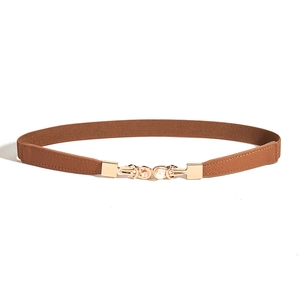 Détail d'une ceinture élastique marron avec boucle en métal doré ornée de perles