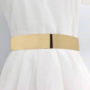Détail de la ceinture dorée à effet miroir métallique portée sur une robe blanche