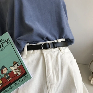 Detail of minimalist black leather belt with silver square buckle on white casual pants