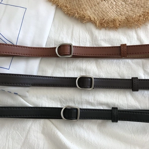 Close-up of narrow PU leather belts in brown and black with silver D-shaped matte buckles