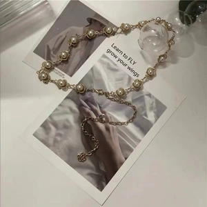 Detalle del cinturón de perlas doradas con cadena ajustable y colgante de flor de rosa