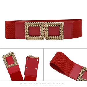 Detail of red elastic waist belt featuring a gold twisted square metal buckle with red inlay