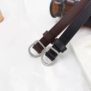 Detail of soft leather belts in black and dark coffee with matte silver oval buckles