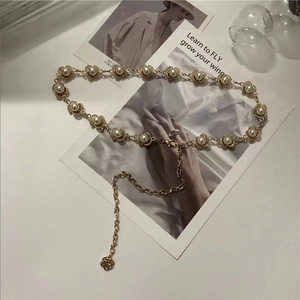 Detalle del cinturón de cadena dorada con flores de perlas y colgante de rosa