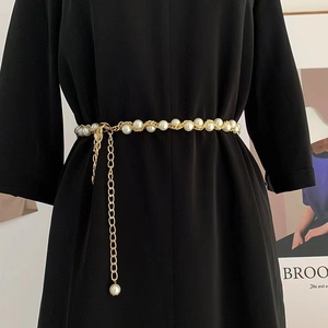 Détail d'une élégante chaîne de taille en perles dorées sur une robe noire chic