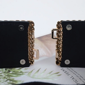 Macro shot of gold wavy metal buckle on black elastic waist belt with screw details
