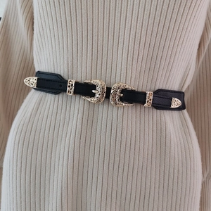 Dettaglio cintura a corsetto vintage nera con fibbie dorate traforate e ornate