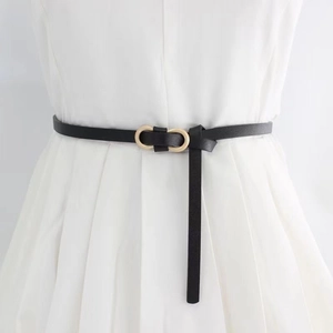 Détail d'une fine ceinture noire avec boucle dorée à double anneau sur robe blanche