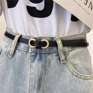 Détail d'une fine ceinture en cuir noir avec boucle double anneau en U dorée mate