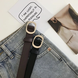 Détails de ceintures fines noires et marron avec boucles dorées sur un jean bleu