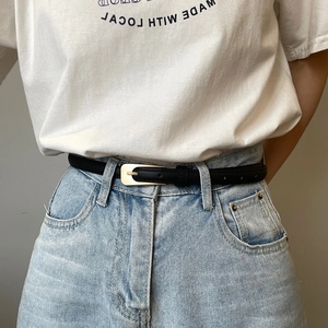 Detail of minimalist black slim belt with silver square buckle on blue denim jeans