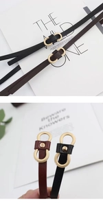 Détail de ceintures fines noires et marron avec boucles dorées à double anneau