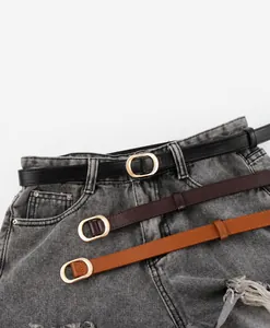 Detailaufnahme von drei Kunstledergürteln mit goldenen Schnallen auf Denim-Shorts