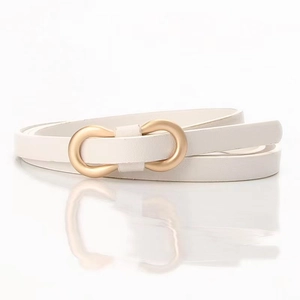 Détail d'une fine ceinture en cuir blanc avec boucle dorée en forme d'infini élégante