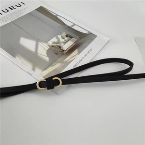 Détail de la fine ceinture noire avec une boucle dorée à double anneau texturée et élégante