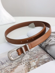 Detailed view of a retro caramel brown leather belt with matte silver pin buckle and rings