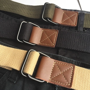 Detail of canvas woven belt featuring metal D-ring buckle and reinforced leather stitching