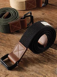 Detail view of canvas belts with double D-ring buckles and leather joints on wood surface