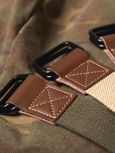 Detail of heavy canvas belts with black double D-ring buckles and leather stitching