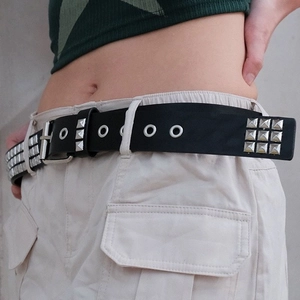 Détail de la ceinture punk en cuir noir avec trois rangées de clous carrés argentés