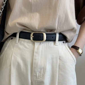 Klassischer schwarzer Ledergürtel für Damen mit matter goldener Schnalle auf weißer Hose