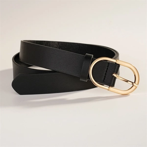 Détail d'une ceinture en cuir noir avec boucle ovale dorée sur une surface blanche