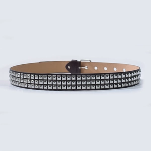 Gros plan sur la ceinture punk noire avec trois rangées de clous pyramidaux argentés et boucle