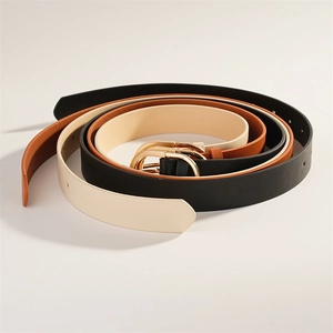 Détail de trois ceintures en similicuir noir, marron et beige avec boucles dorées