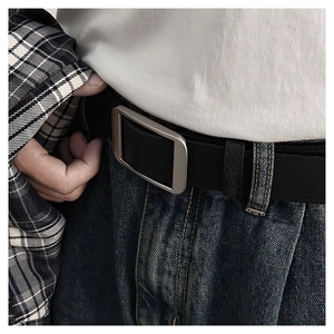 Close-up of minimalist black leather belt with matte silver square buckle on jeans