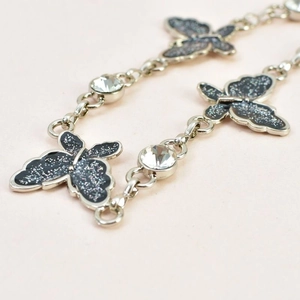 Detail of silver metal waist chain featuring black glitter butterfly charms and crystals