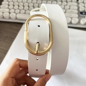 Détail de la ceinture en cuir blanc motif litchi avec une boucle ovale en métal doré