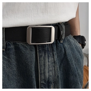 Detail of a minimalist black leather belt with matte silver buckle on blue jeans