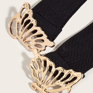 Detailopname van de gouden holle vlindergesp op een zwarte elastische taille riem