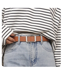 Detail of a brown leather belt with silver metal buckle worn on blue denim jeans