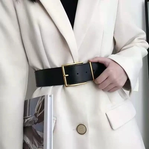 Women's black leather belt with a large gold square buckle on a white blazer outfit