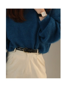 Detail eines schmalen schwarzen Ledergürtels mit Goldschnalle zu blauem Mohair-Pullover