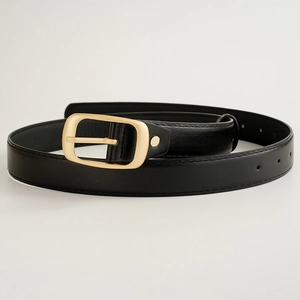 Détail d'une ceinture en similicuir noir avec une boucle ardillon dorée pour femme