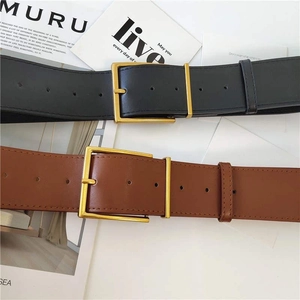 Detailed view of classic black and brown leather belts with gold buckles on magazines