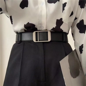 Minimalist black leather waist belt with matte silver buckle on black trousers