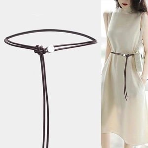 Détail d'une fine ceinture en cuir nouée avec boucle ronde en métal sur une robe