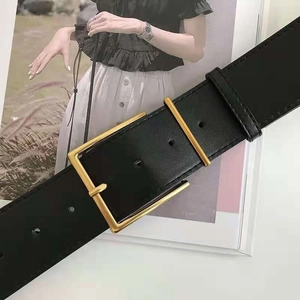 Detail of black leather belt showing golden rectangular buckle and fine stitching texture