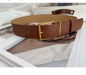 Close-up of a vintage brown leather belt with a matte gold rectangular buckle